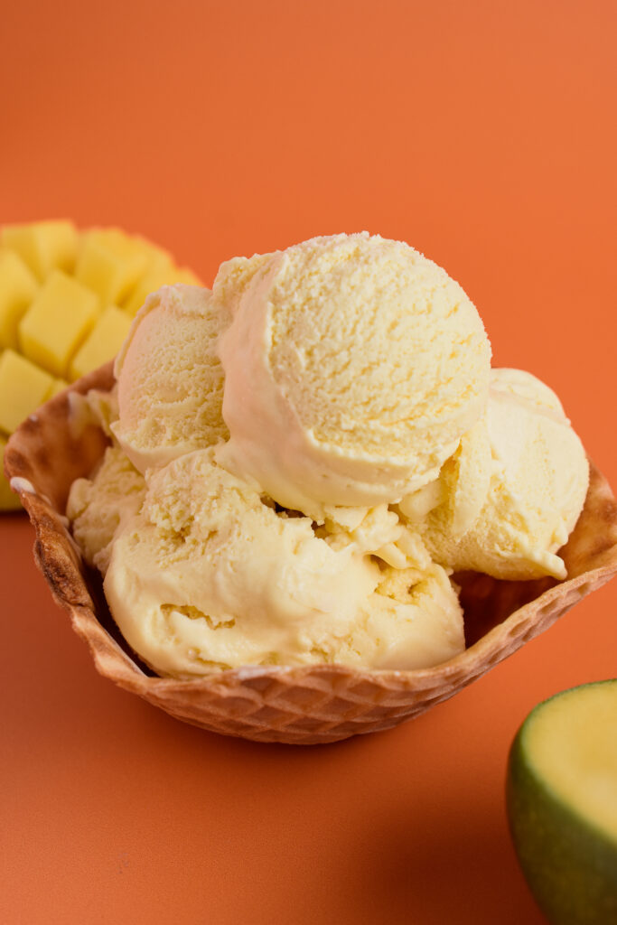 scoops of mango ice cream in a waffle cone